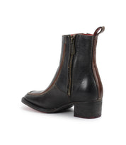 The Bitsy boot by Bed|Stü is a black leather ankle boot with brown trim, featuring a side zipper, pull tab, and stacked heel. Shown on a white background, these stylish boots have a rounded toe for classic appeal.