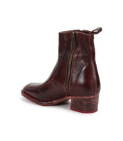 The Bed|Stü Bitsy is a dark brown leather ankle boot featuring a side zipper, low stacked heel, and back pull tab—photographed on a plain white background, it’s an essential addition to any collection of classic leather boots.