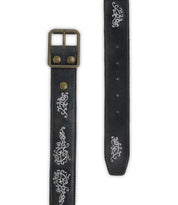 Blaze JB by Bed|Stü is a black full-grain leather belt featuring an antique-finished brass buckle and silver embroidered scrollwork along the strap, with adjustable holes for a customized fit.