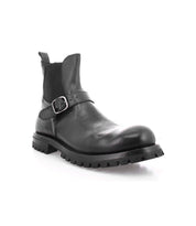 Boast by Bed|Stü is a black leather ankle boot crafted from full-grain leather, featuring a side buckle, elastic panel, pull tab, and thick rubber lug sole—shown on a white background. This classic men's Chelsea boot combines the enduring quality of Italian leather boots with modern details for everyday wear.