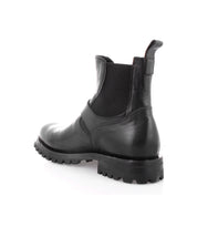 The Boast Chelsea Boot by Bed|Stü is a men's boot crafted from full-grain black leather, featuring elastic side panels and a rugged rubber sole, shown from a rear side angle on a white background.