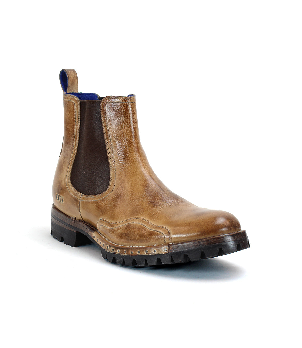 Introducing the Bed|Stü Brady Trek: a brown leather Chelsea boot featuring dark elastic side panels, a blue pull tab, decorative stitching, and a rugged black treaded outsole—shown on a white background. This timeless Brady Trek boot blends classic style with everyday durability.