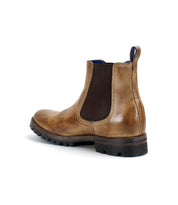 Introducing the Bed|Stü Brady Trek: a timeless Chelsea boot crafted from brown leather, showcasing a black elastic side panel, blue interior lining, pull tab, and a thick black treaded outsole, displayed on a white background.