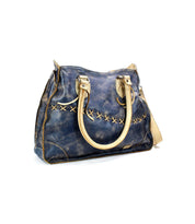 The Bruna handbag by Bed|Stü, featuring blue distressed leather with beige handles and front cross-stitch detailing, is showcased against a white background to emphasize its stylish two-toned leather design.