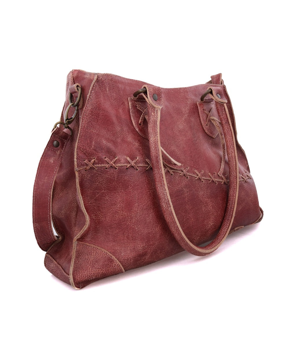 The Bed|Stü Bruna is a large reddish-brown leather handbag with double handles, visible stitching, and padded straps, featuring a detachable shoulder strap for easy crossbody wear, shown on a white background.