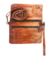 Cadence by Bed|Stü is a brown 3-in-1 wallet and crossbody clutch, crafted from luxurious vegetable-tanned leather. Featuring multiple zippers, credit card slots, a detachable strap, and a wristlet attachment, it is shown here on a white background.