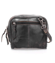 The Bed|Stü Capture is a small, black leather crossbody bag featuring a front zipper pocket, worn edges, and an adjustable strap; this compact handbag is displayed against a white background.