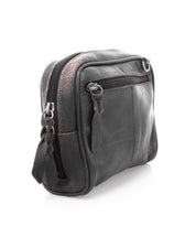 The Bed|Stü Capture, a small black leather crossbody bag with a front zipper pocket and visible scuff marks, is photographed on a white background—this compact handbag exudes both character and timeless style.