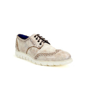 The Bed|Stü Cayuga II is a light beige leather derby shoe with classic brogue detailing and decorative perforations, accented by dark laces and set atop a white rubber sole, shown against a plain white background.