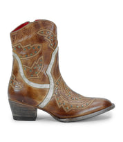 The Bed|Stü Chamise is a brown leather cowboy boot featuring decorative stitching, metallic accents, and small studs. This classic western boot is displayed in profile with a low heel and rounded toe.