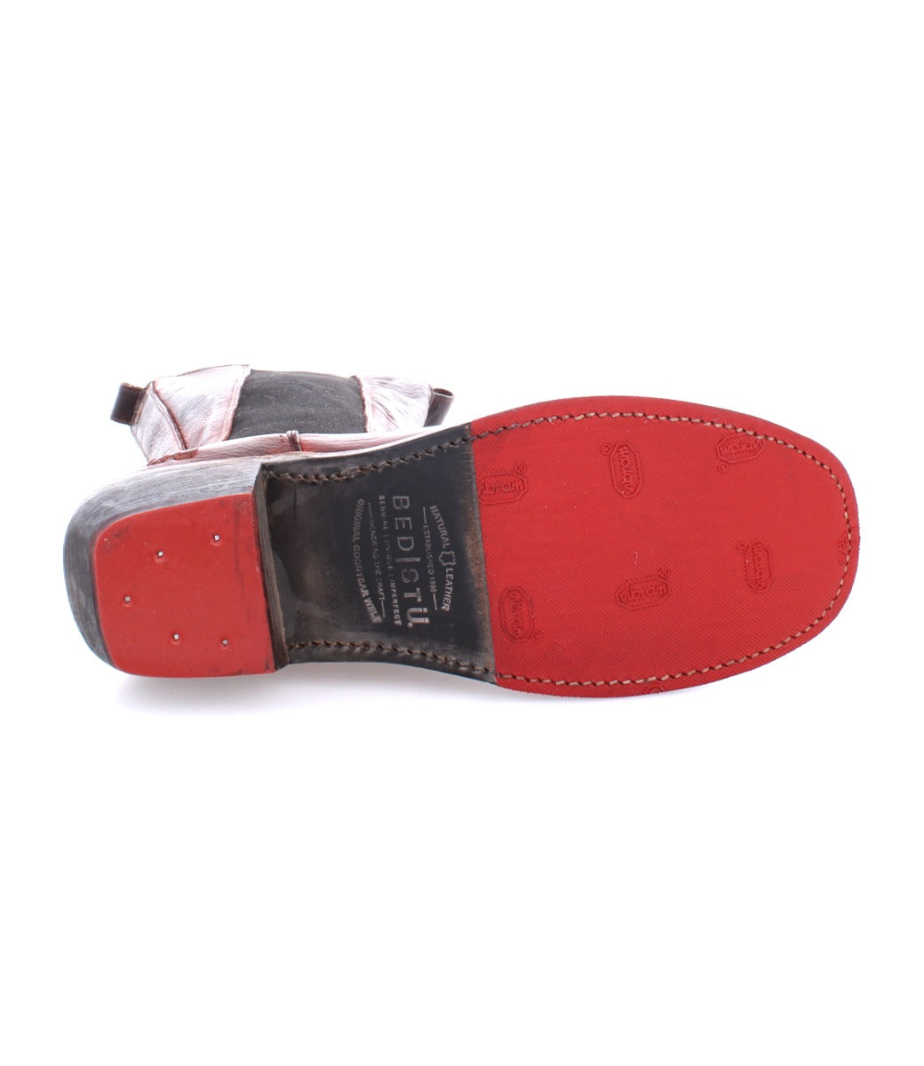 A close-up of the red sole and western heel of the Bed|Stü Clarisse red leather boot, featuring visible stitching, branding, and small metal tacks.