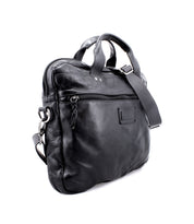 The Bed|Stü Conclusion messenger bag, crafted from black leather, includes a dedicated laptop compartment, a front zippered pocket, top handles, and an adjustable shoulder strap, displayed against a white background.