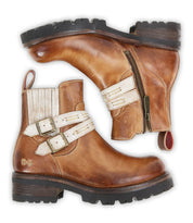 Bed|Stü "Daring" ankle boots in brown leather, featuring a rugged design with cream straps, buckles, and side zippers, displayed from the side and top view on a white background.