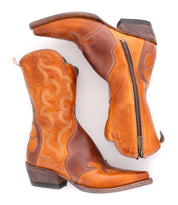 The Bed|Stü Deuce is a pair of mid-calf brown Western boots, crafted from vegetable-tanned leather with detailed stitching and convenient side zippers, shown against a white background.