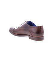 The Bed|Stü Donatello II is a brown leather dress shoe featuring brogue detailing and a classic cap-toe design, shown from the back right side on a white background.
