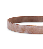A close-up of the Bed|Stü Drifter brown leather belt with a metal buckle, shown coiled on a white background. The textured leather strap and minimal design make the Drifter a versatile accessory for any outfit.
