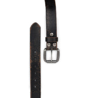 A close-up of the Bed|Stü Drifter, featuring a worn black textured leather strap with a metal buckle and multiple adjustment holes, displayed in a minimal style on a white background.