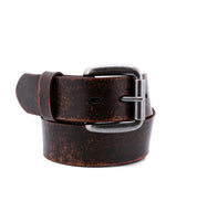 Introducing the Drifter belt by Bed|Stü: a rolled-up, dark brown accessory crafted from textured leather with a distressed finish and complemented by a sleek silver metal buckle, all showcased on a white background for a modern, minimal style.