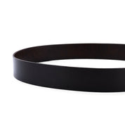 The Drifter belt by Bed|Stü features a textured black leather strap and a metal buckle, arranged in a circular shape against a white background to showcase its minimalist style.