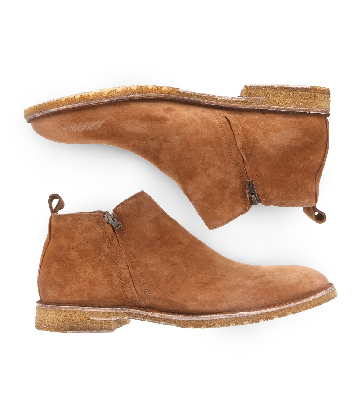 The Bed|Stü Evade is a pair of men's brown suede boots handcrafted in Italy, featuring dual side zippers, cork soles, and pull tabs. The boots are shown from the side and bottom views against a white background.
