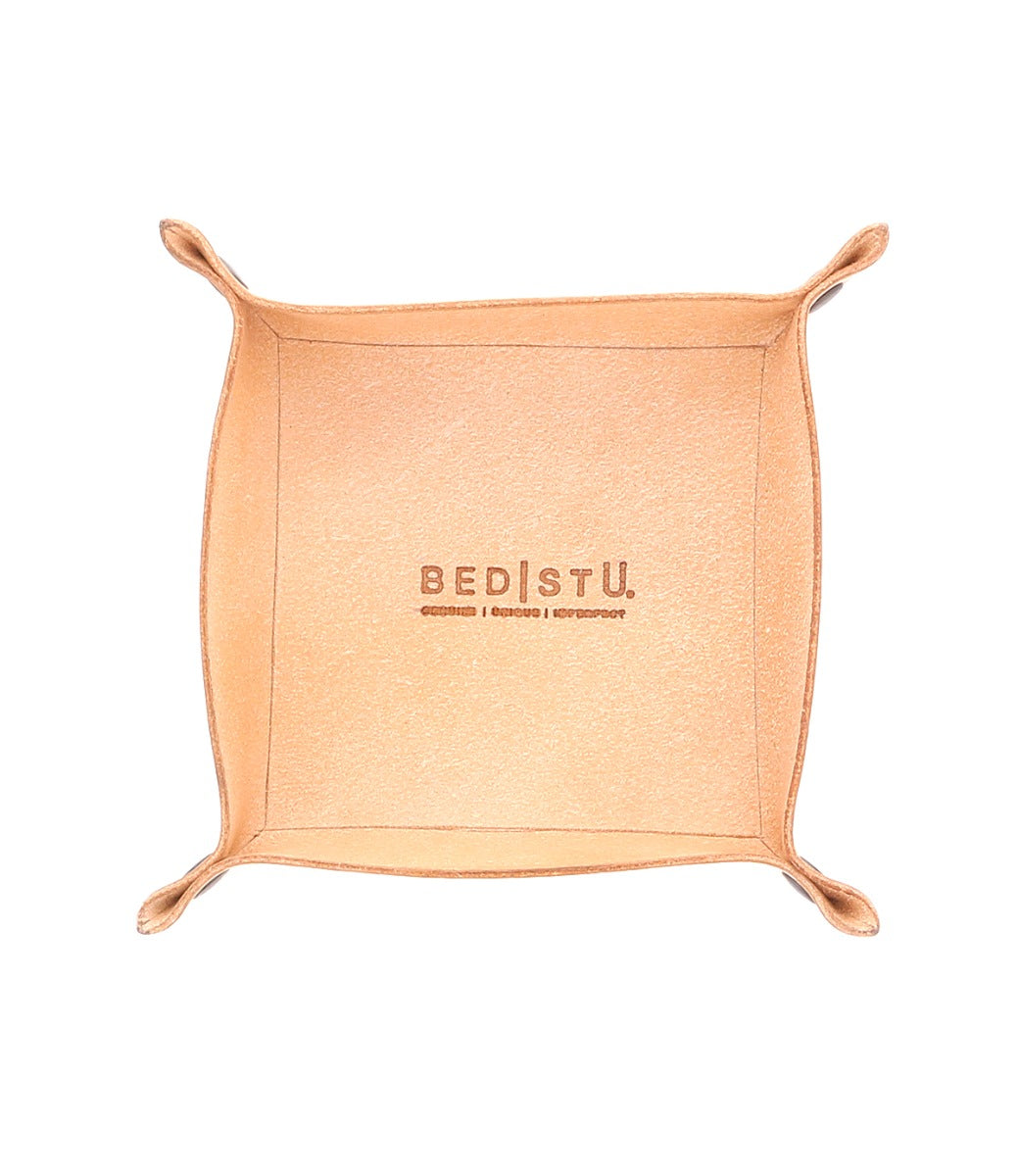 The Expanse Catchall Tray by Bed|Stü is a square tan leather valet tray featuring raised edges and rounded corners, embossed with the "Bed|Stü" logo and additional small text below, shown on a white background—ideal for organizing your essentials.