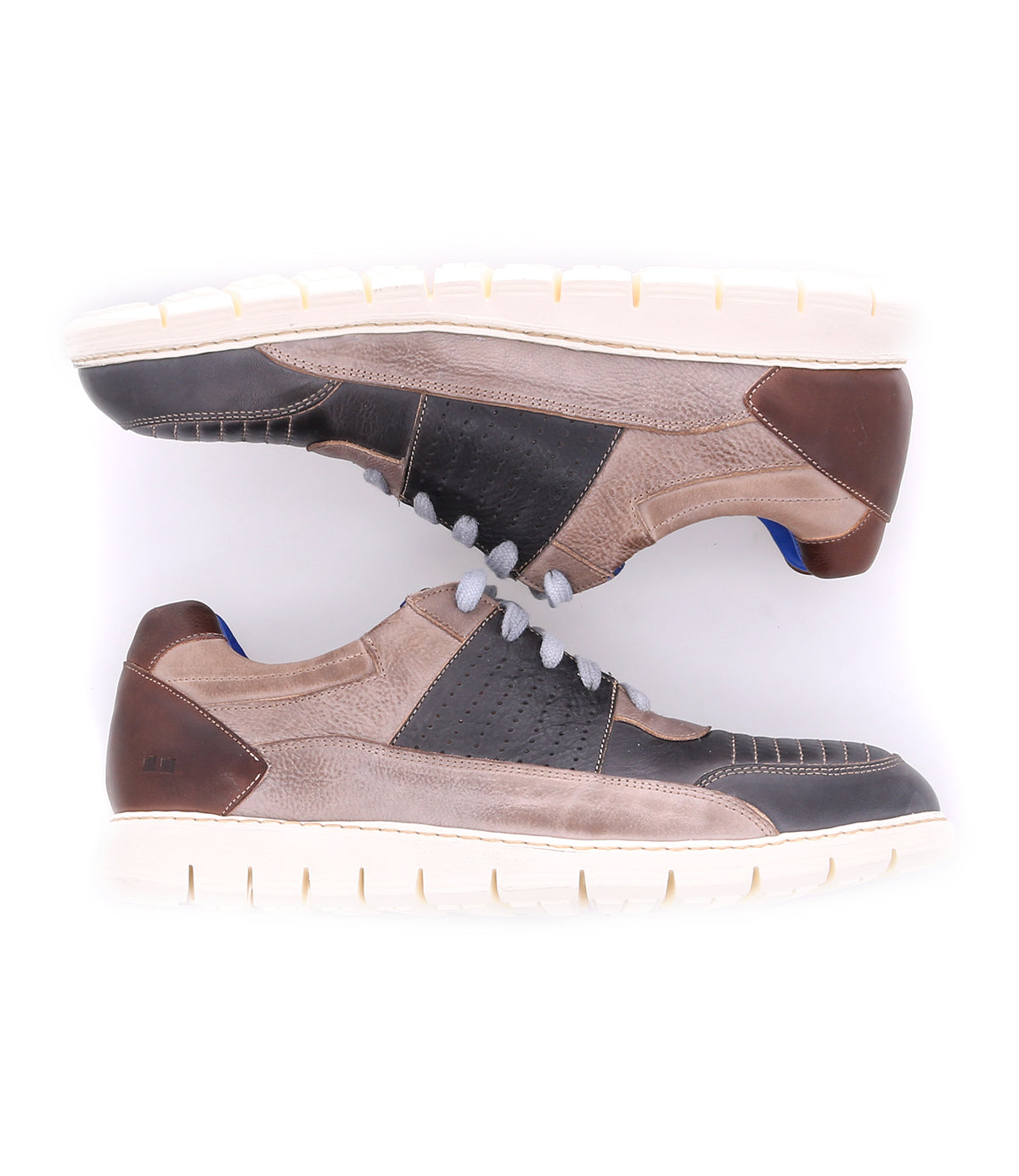 Two Bed|Stü Fairman casual men's sneakers are placed side by side, soles facing outward. The shoes feature a three-tone leather design in beige, brown, and black, complemented by white lightweight soles and gray laces.