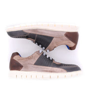 Two Bed|Stü Fairman casual men's sneakers are placed side by side, soles facing outward. The shoes feature a three-tone leather design in beige, brown, and black, complemented by white lightweight soles and gray laces.