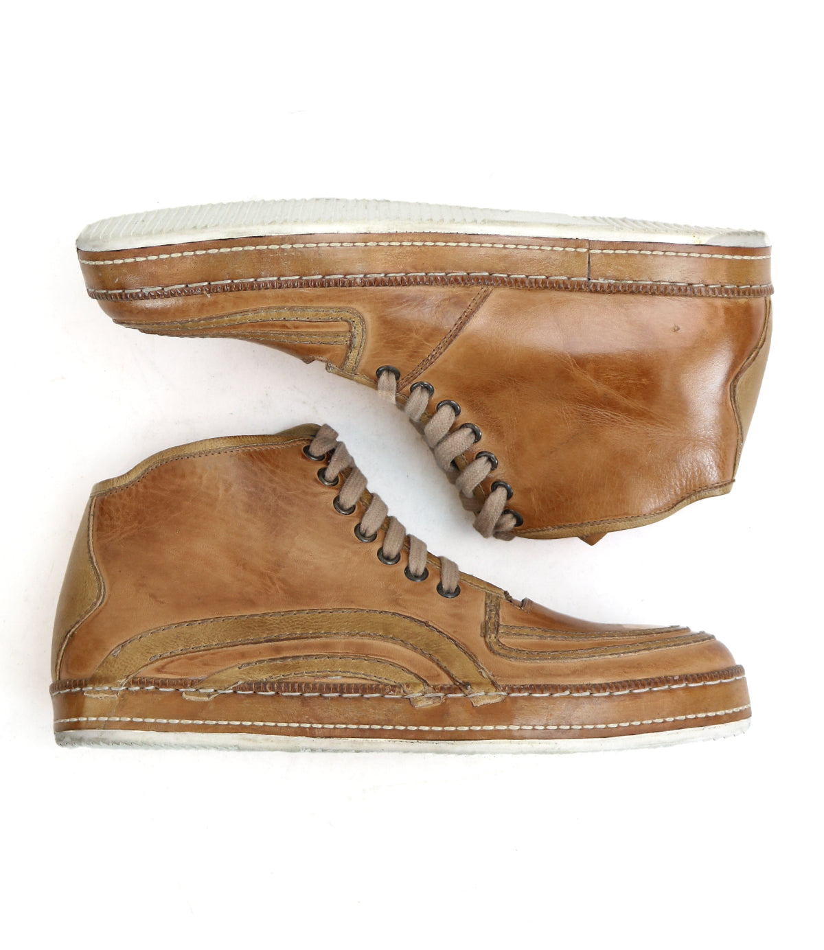 The Bed|Stü Formation sneakers feature rich brown leather in a classic high-top silhouette with crisp white soles. One shoe is laid flat while the other rests on its side, highlighting the detailed stitching, lace accents, and distinctive leather paneling inspired by vintage court sneaker design.
