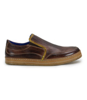 The Bed|Stü Freestyle is a brown leather slip-on sneaker featuring yellow leather trim, a blue interior lining, and a tan rubber sole, shown in side profile for a comfortably stylish look.