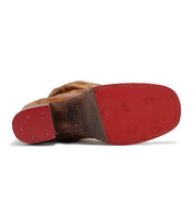 The image displays the underside of the Bed|Stü Leilani boot, crafted from brown leather with a red rubber sole and heel. Visible stitching and branding accent the sole, while elegant ruching along the upper enhances the refined look of this standout style.