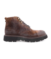 The Bed|Stü Goer is an Italian work-style boot crafted from brown oiled suede leather, featuring a lace-up cap-toe design, black rugged sole, visible stitching, and metal eyelets. Shown in profile on a plain white background, the Goer combines durability with timeless style.