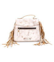 Bed|Stü Hidden handbag in beige soft leather, featuring a structured silhouette, a front zipper pocket, top handle, and long fringe detailing on both sides, displayed against a white background.
