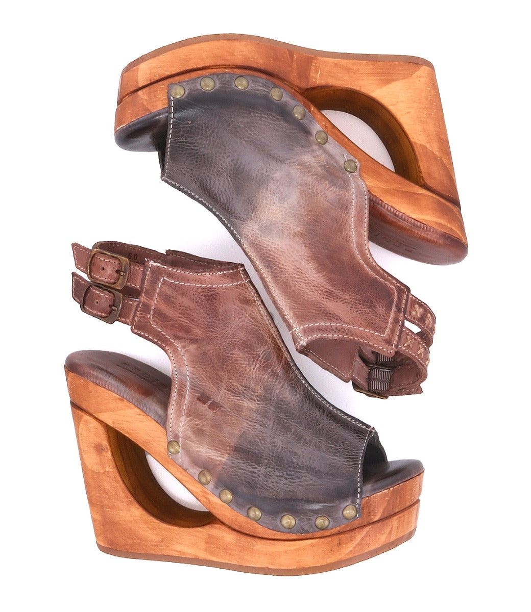 A pair of Imelda brown leather platform wedge sandals by Bed|Stü, featuring wooden soles, an open-toe silhouette, metal rivets, and double adjustable ankle buckles, displayed side by side.