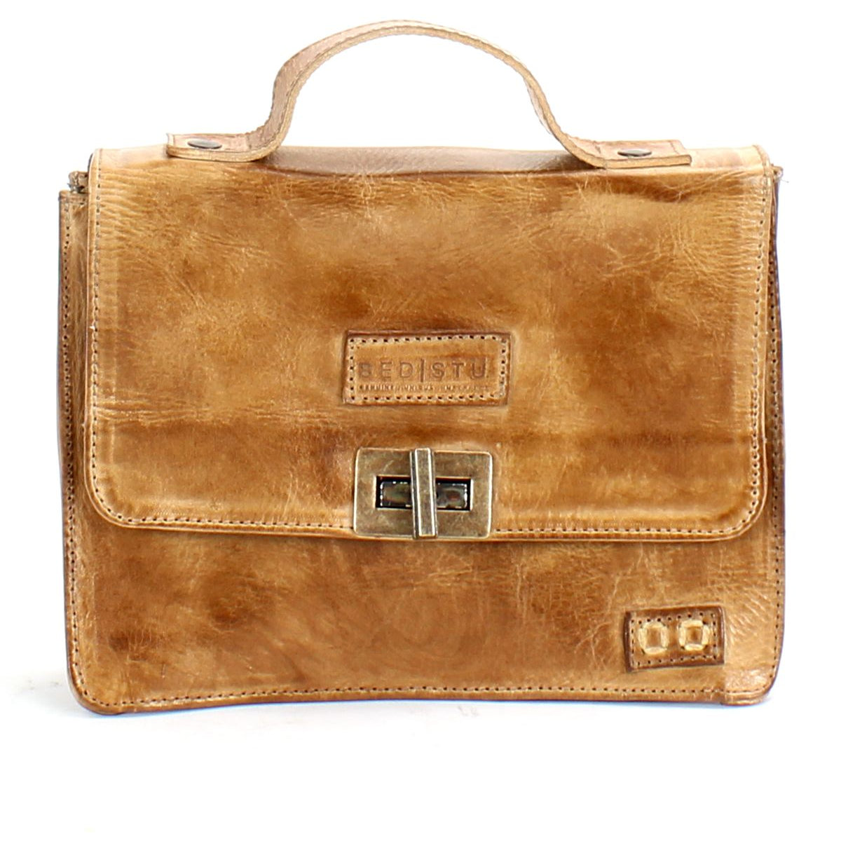 The Bed|Stü Improv is a tan leather briefcase featuring a top handle, front flap secured by two metal clasps, a rectangular embossed logo on the front, and an adjustable crossbody strap for versatile carrying options.