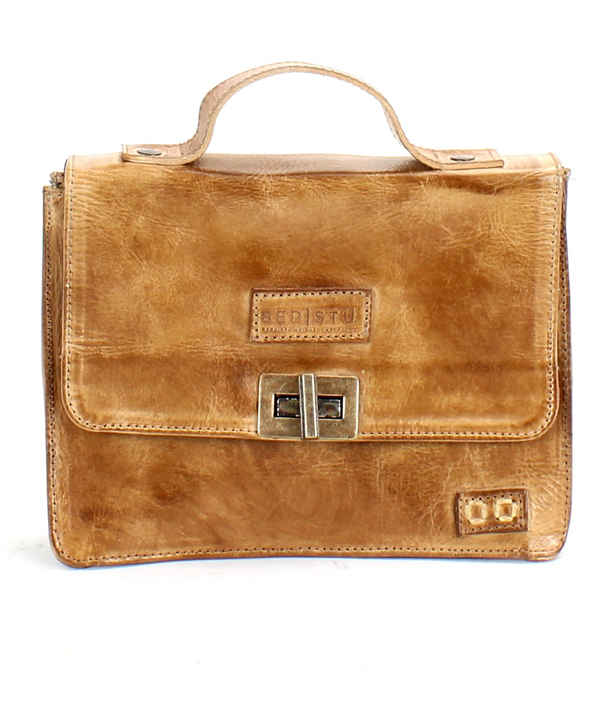 The Bed|Stü Improv is a tan leather briefcase featuring a top handle, front flap secured by two metal clasps, a rectangular embossed logo on the front, and an adjustable crossbody strap for versatile carrying options.