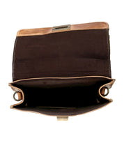 The Bed|Stü Improv bag is shown open with its brown leather flap lifted, top handle and crossbody strap visible, revealing its empty black fabric-lined interior with divided compartments, set against a white background.