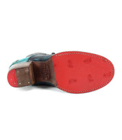 The Bed|Stü Judgement cap toe dress shoe is displayed from the bottom, showcasing its distinctive red textured sole with small imprints and a stacked leather heel.