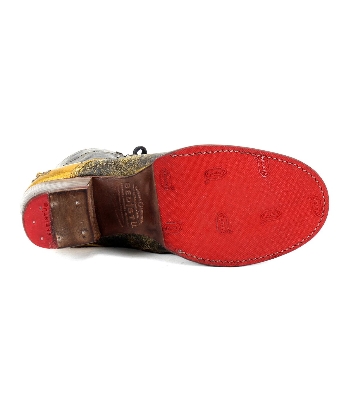 The Bed|Stü Judgement boot is pictured from the bottom, showcasing its bright red sole with visible stitching and embossed text and patterns, along with a distinctive cap toe and a sturdy block heel.