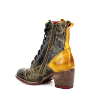 The Bed|Stü Judgement boot is a worn, leather lace-up design featuring a medium block heel, cap toe, side zipper, and a distressed yellow and black leather finish, shown against a white background.