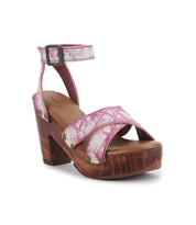 The Kalah platform sandal by Bed|Stü features a pink and white pattern, sustainably sourced wooden heel, crisscross straps, an adjustable ankle strap with buckle, and metal stud detailing.