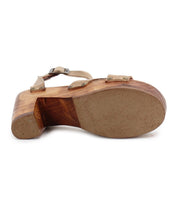 The Bed|Stü Kalah sandal is pictured from the bottom-up, showcasing its sustainably sourced wooden platform heel, the studs along the straps, and an adjustable ankle strap.