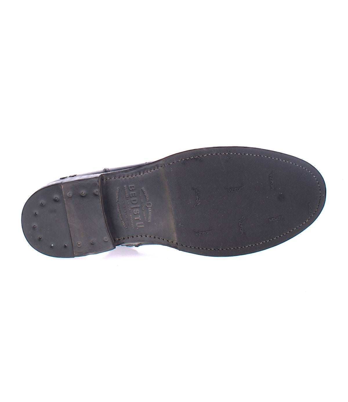 The image shows the underside of the Bed|Stü Kaldi black leather dress shoe, featuring visible stitching, a nailed heel, and embossed branding on the sole—details that reflect the craftsmanship characteristic of a classic or refined leather boot.