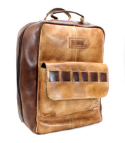 The Kamet laptop bag by Bed|Stü is crafted from vegetable-tanned tan and brown leather, featuring a front flap pocket, sturdy top handle, and visible stitching. Woven leather accents and an embossed Bed|Stü logo on the front further enhance its refined design.