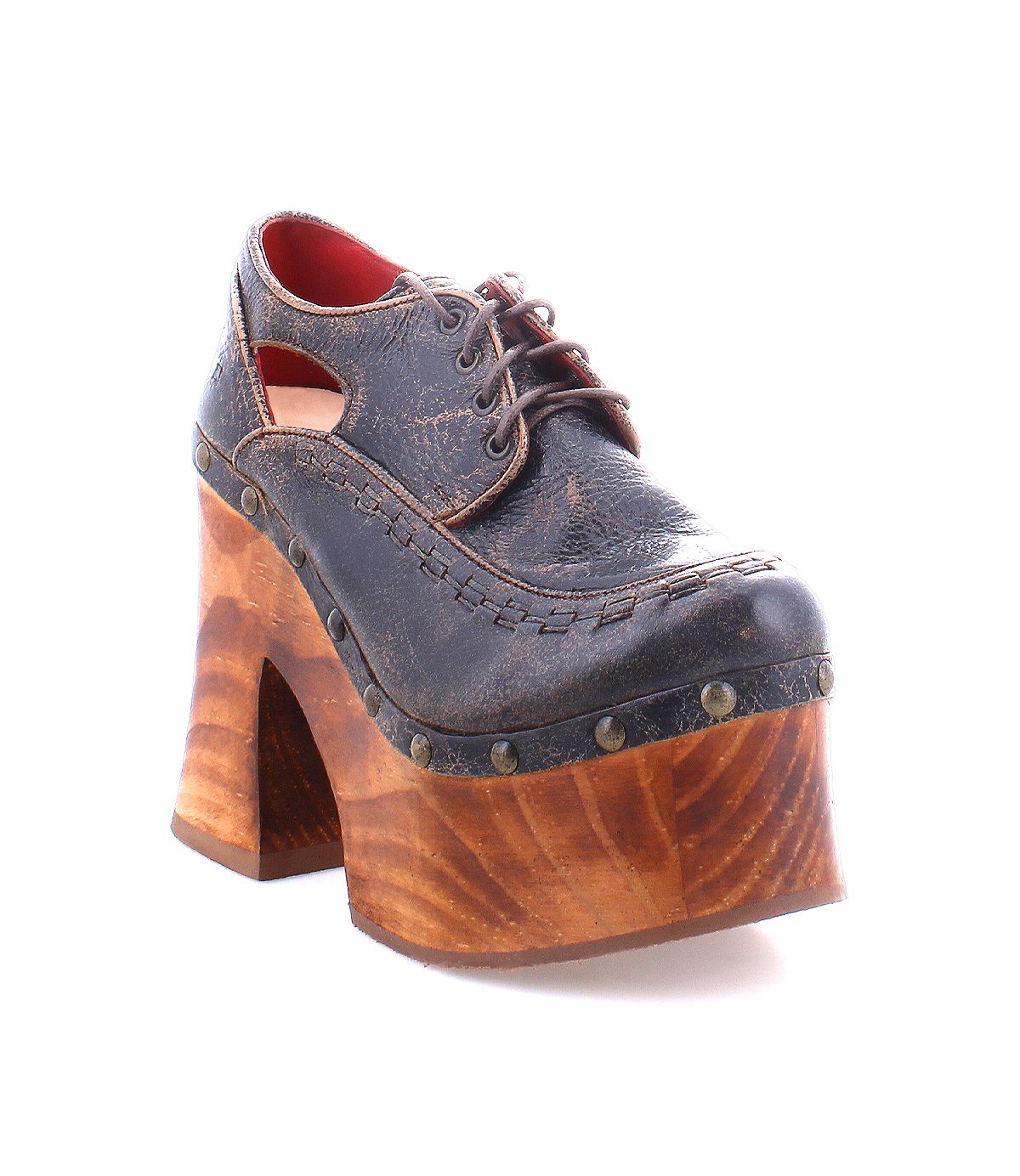 A single Bed|Stü Karaoke vintage-inspired lace-up platform shoe, featuring a dark leather upper with cutout sides and a chunky wooden platform sole adorned with metal studs, reminiscent of an iconic 70s style, displayed on a white background.