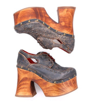 Two Bed|Stü Karaoke vintage 70s shoes with chunky wooden platforms, high heels, dark leather uppers, brass studs, and cut-out details are shown side by side on a white background.