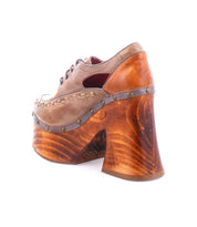 A single Bed|Stü Karaoke shoe in brown, showcasing a chunky wooden platform and sculpted heel, with visible stitching, brass rivet accents, and a fashionable lace-up design—all photographed on a white background.