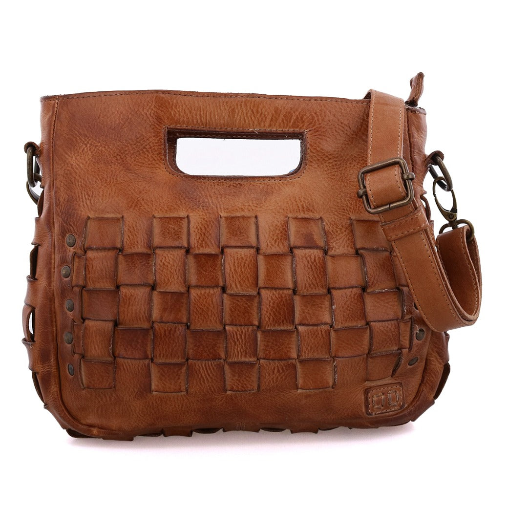 Introducing Keiki by Bed|Stü—a brown leather handbag featuring a woven front design with metal studs, a unique cut-out handle, and an adjustable strap. With its secure zip-top closure, the Keiki seamlessly combines fashion and function for everyday use.