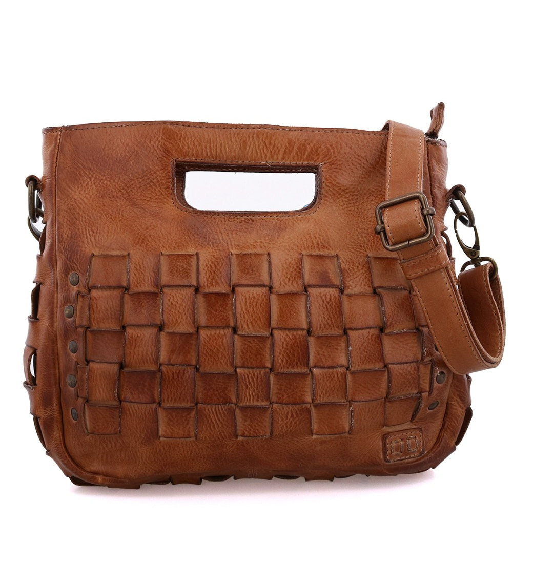 Introducing Keiki by Bed|Stü—a brown leather handbag featuring a woven front design with metal studs, a unique cut-out handle, and an adjustable strap. With its secure zip-top closure, the Keiki seamlessly combines fashion and function for everyday use.