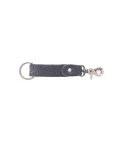 The Bed|Stü Keygrab is a black full grain leather keychain featuring a metal keyring on one end and a swivel clip clasp hook on the other, shown against a white background.