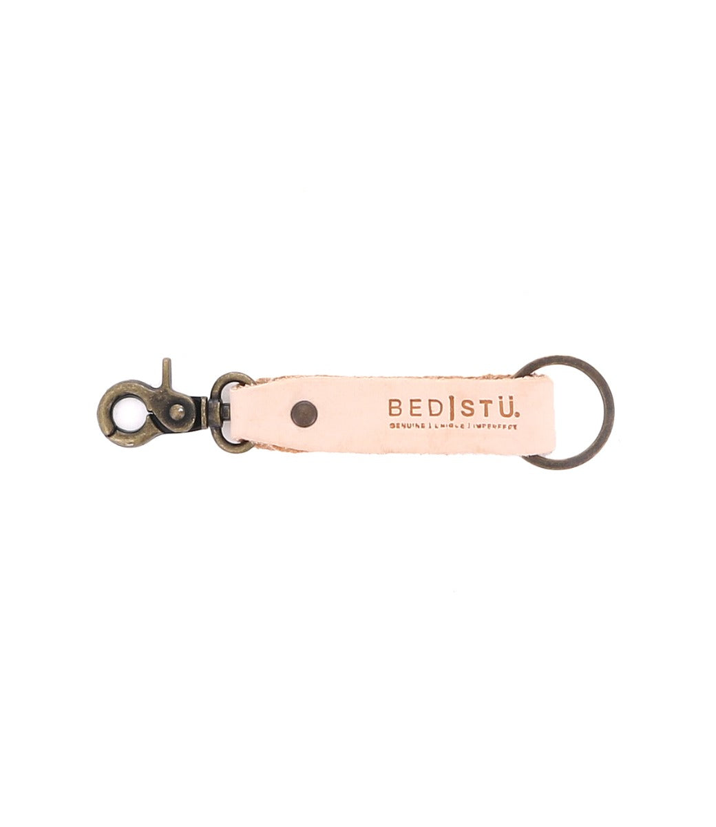 Introducing the Bed|Stü Keygrab: a beige full grain leather keychain with a metal swivel clip and keyring, featuring the Bed|Stü logo and embossed with the words "Genuine | Unique | Imperfect." Perfect as a stylish key organizer.